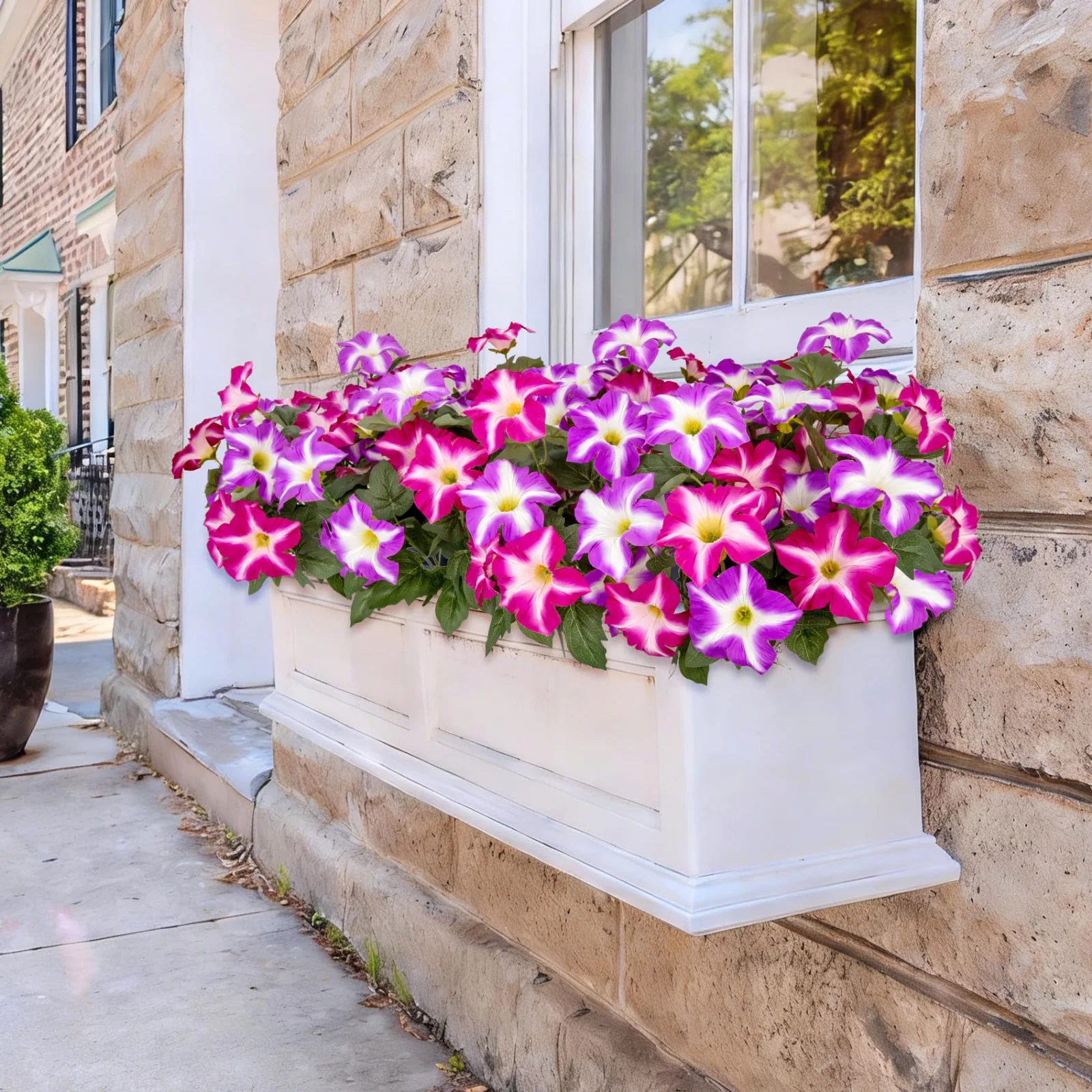 A window box filled with mixed artificial flowers under a window with blue siding